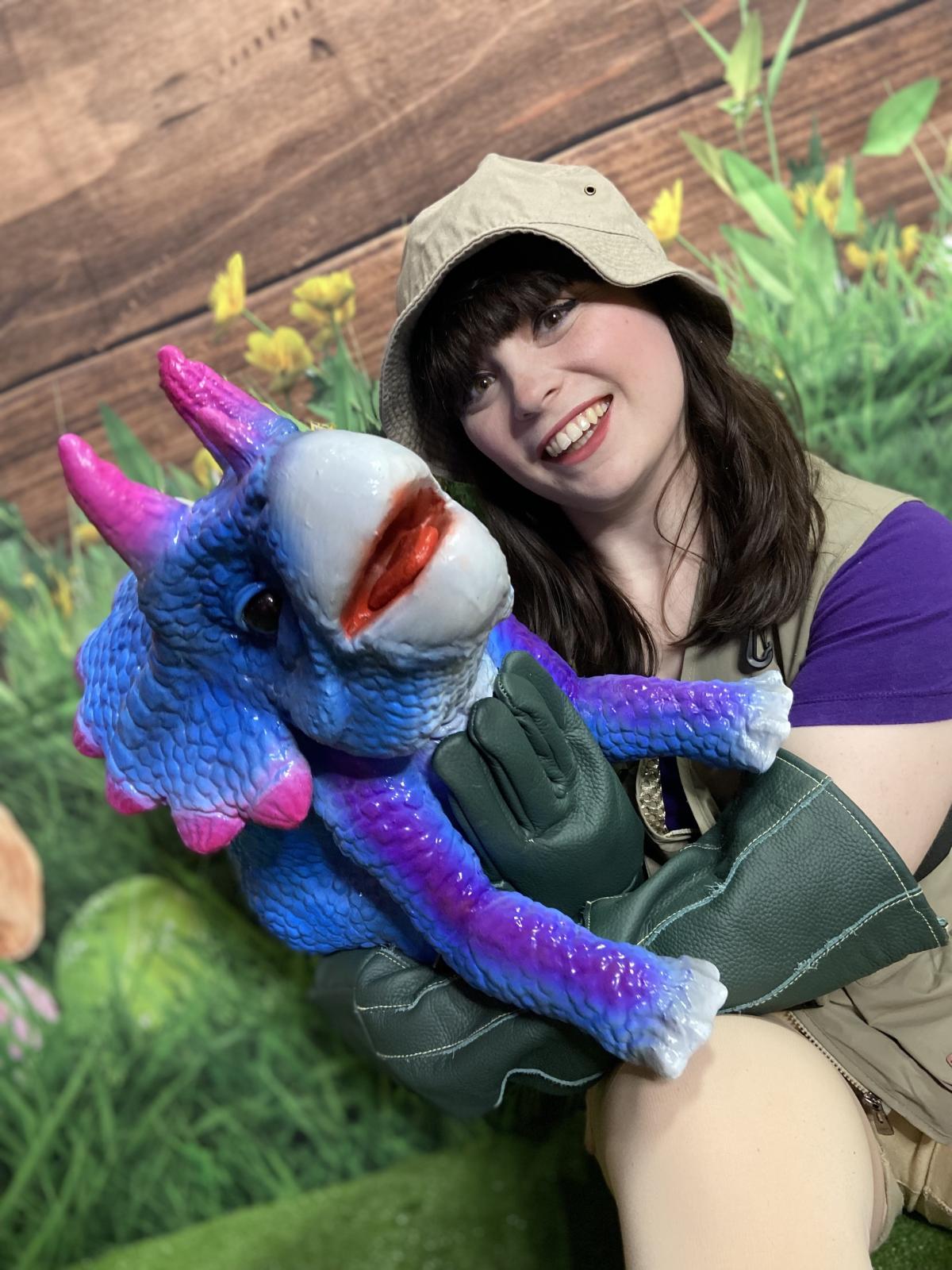 woman in safari hat holding baby triceratops dinosaur